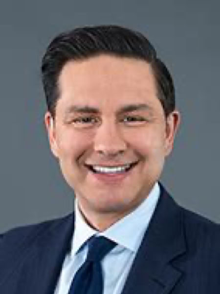 Man in a suit and tie smiling against a gray background.